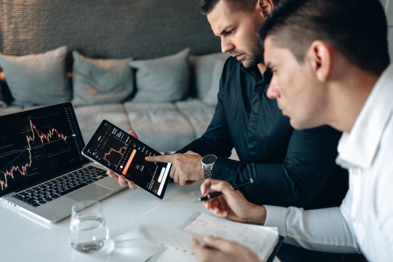 men sitting on a couch looking at a laptop