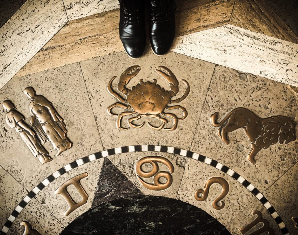 a pair of feet in the sand next to a stone sculpture