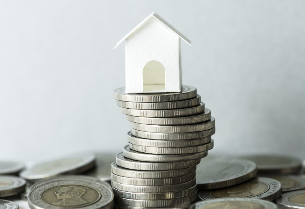 a stack of coins with a paper house on top