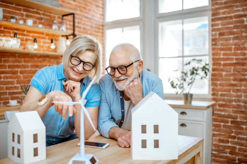Senior couple with house models and toy wind turbine at home