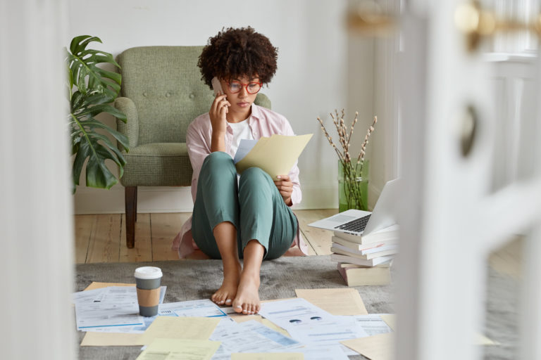 Busy lady with Afro hairstyle, studies attentively job description, looks at documents, has conversa